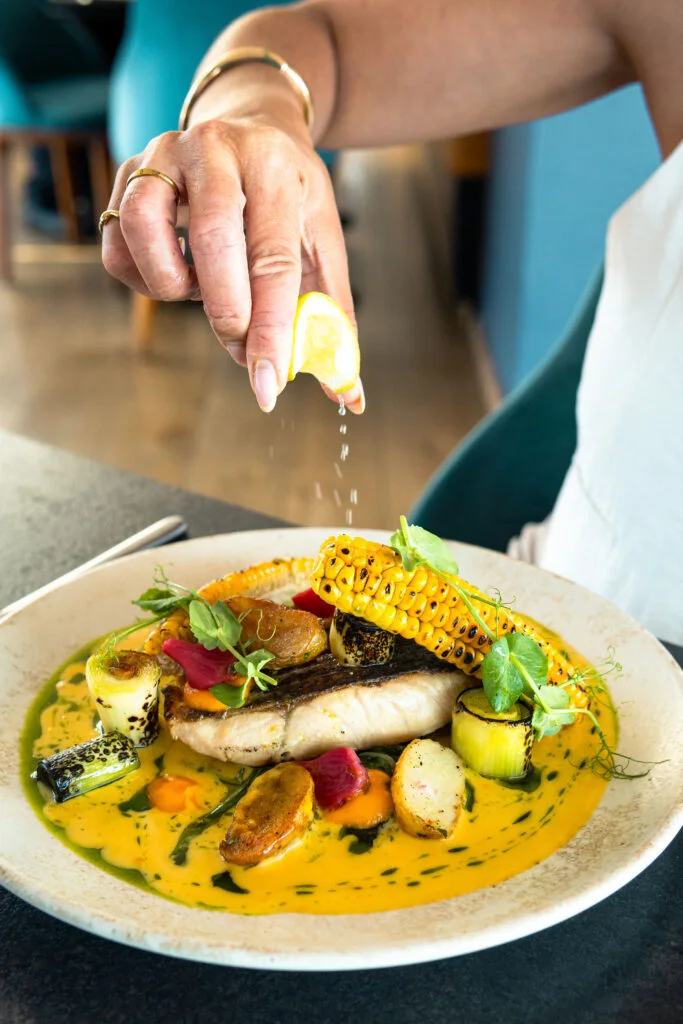 A fish main being finished with fresh lemon at Utopia